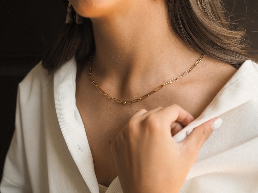 a woman wearing a white shirt and a gold necklace