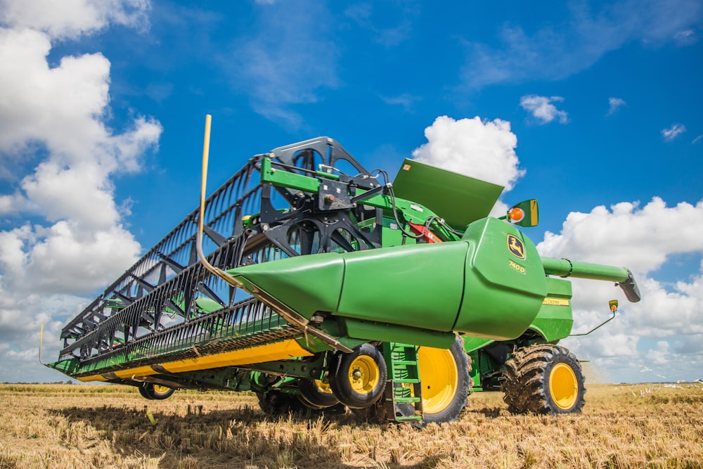 a large green tractor with a bale of hay on it's back