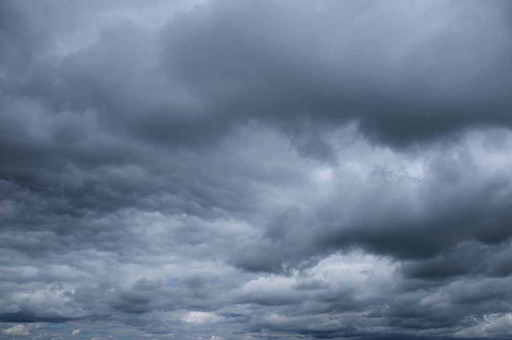 a cloudy sky over a beach with a boat in the water