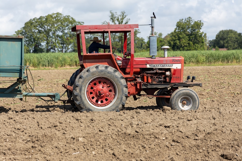 a red tractor and a blue trailer in a field