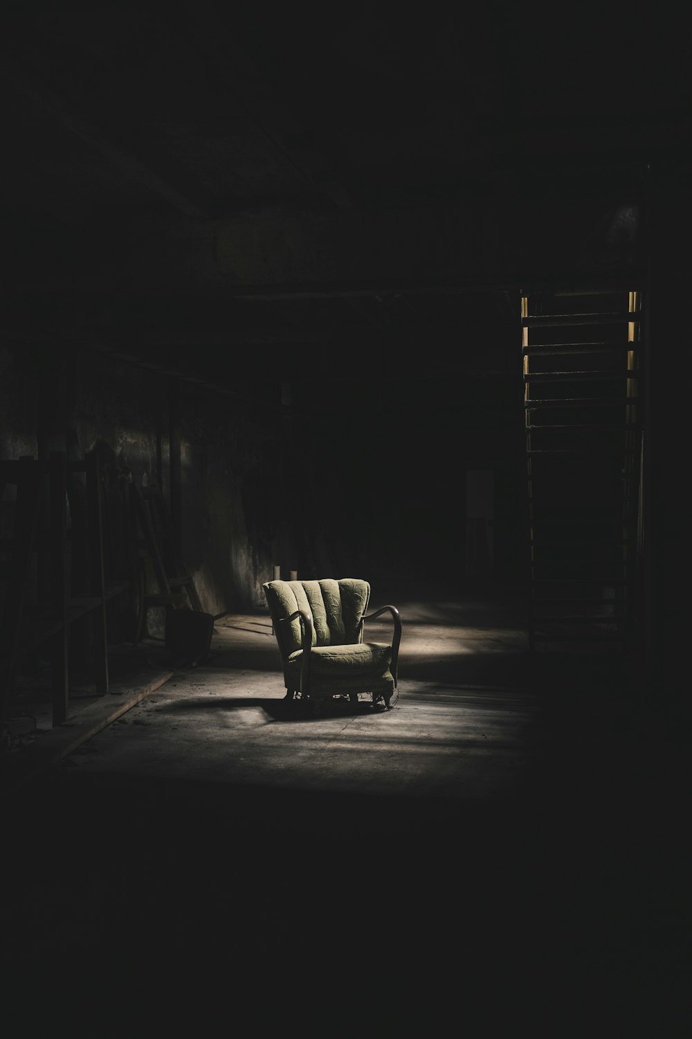 una stanza buia con una sedia e una scala