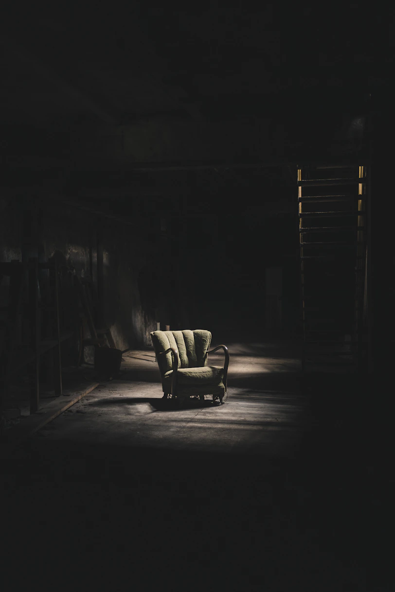 a dark room with a chair and a ladder