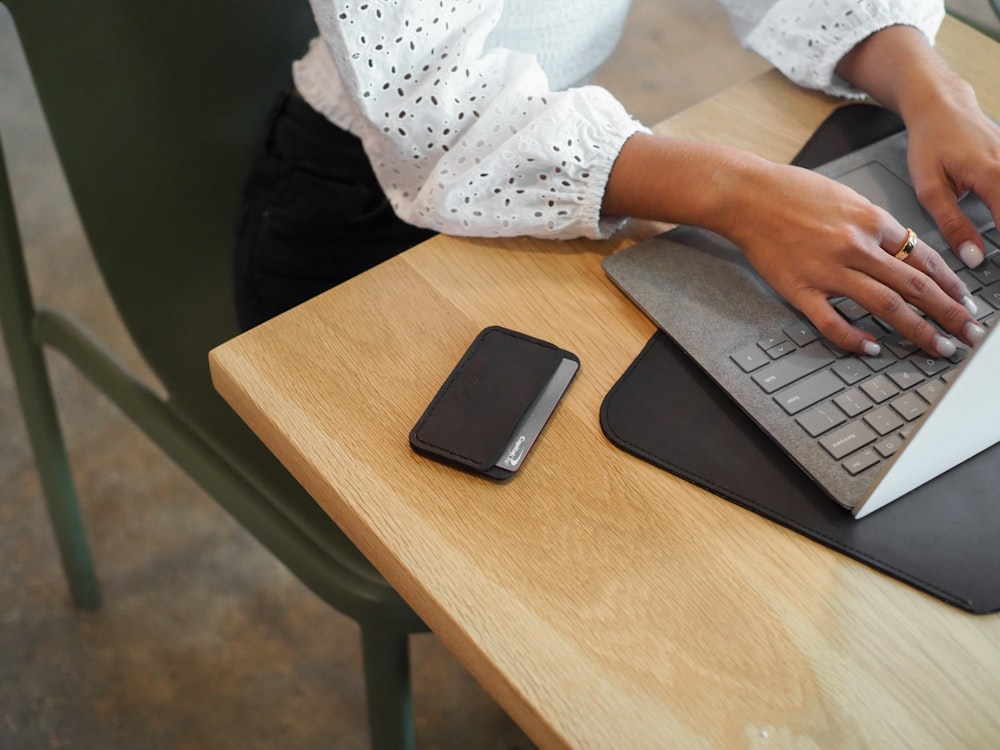 a woman using a laptop computer on top of a wooden table