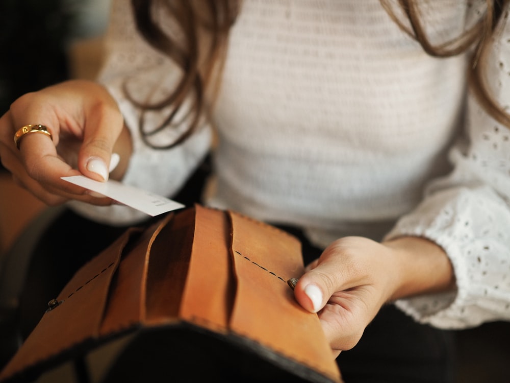 uma mulher segurando uma carteira e um pedaço de papel