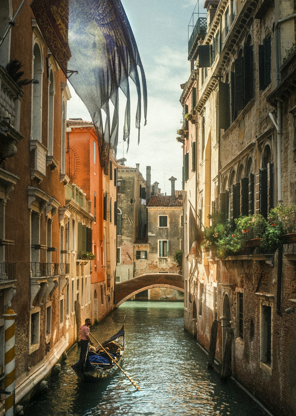 a man riding a boat down a narrow canal