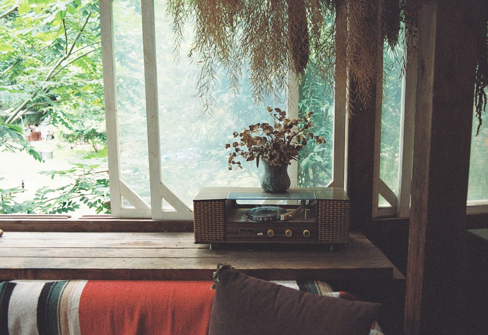 a table with a radio and a vase of flowers on top of it