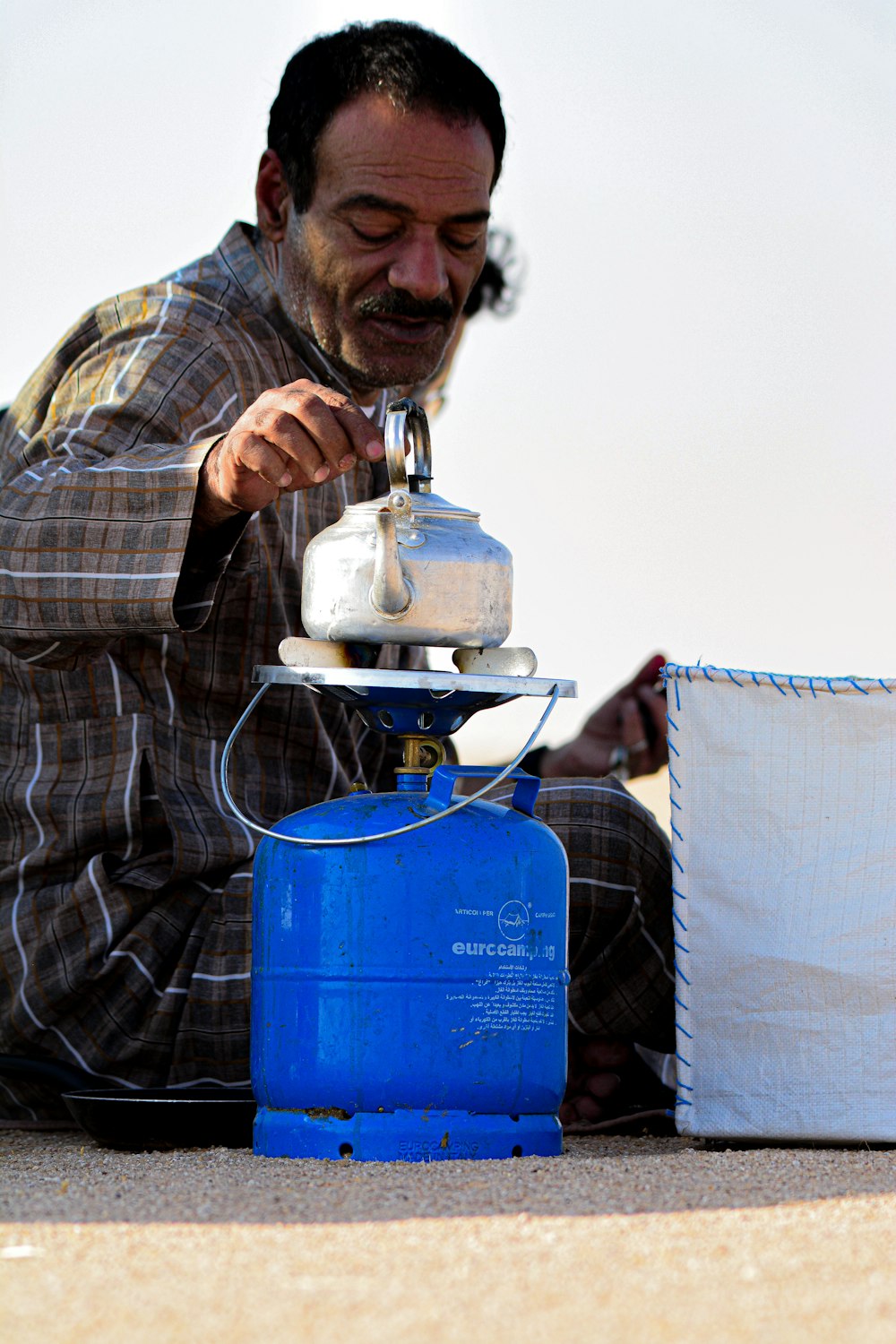 a man sitting on the ground pouring water from a jug