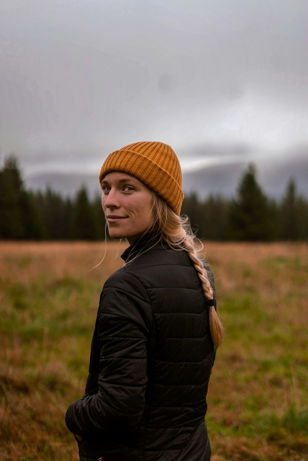 a woman standing in a field wearing a hat