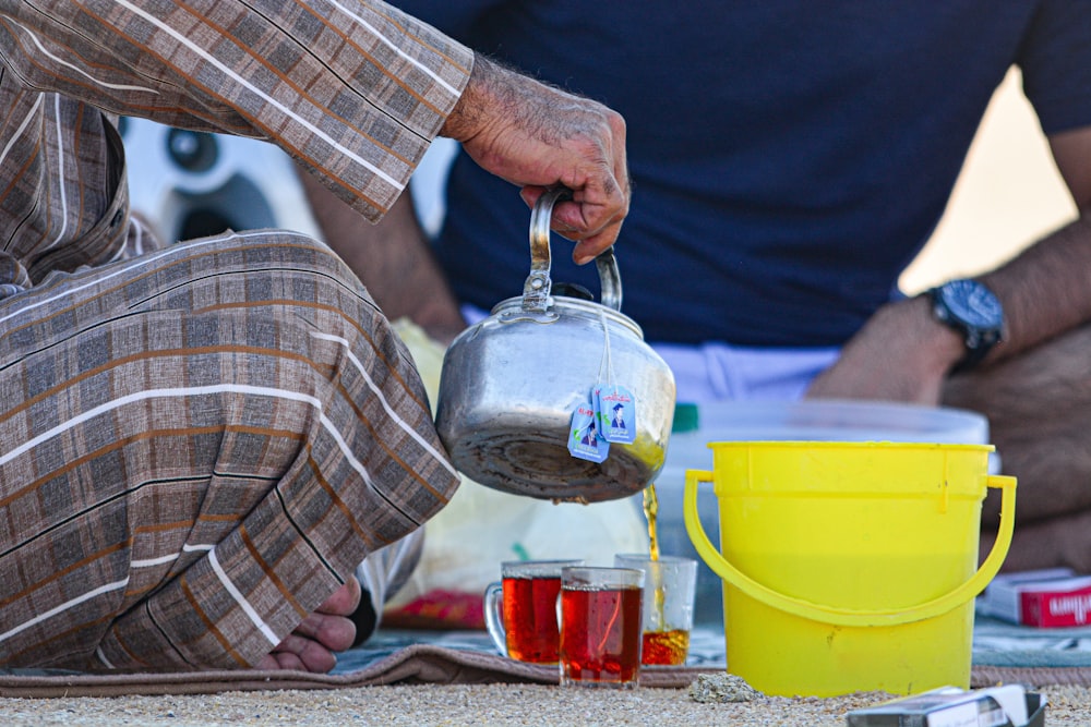 a man sitting on the ground pouring tea into a cup