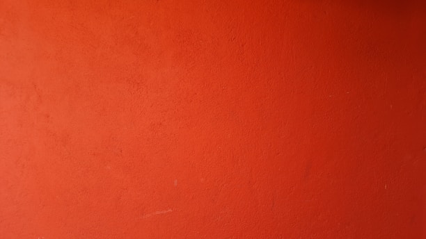 A skilled painter applying a smooth coat of orange paint on a modern interior wall.