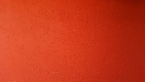 A vibrant wall freshly painted in warm sunrise orange, showcasing smooth and even coverage.