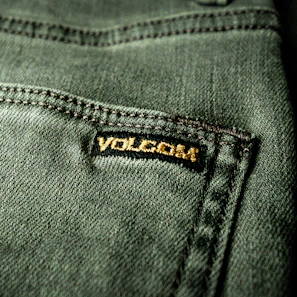 Close-up of a gold-embroidered logo on a black fabric, highlighting fine craftsmanship.
