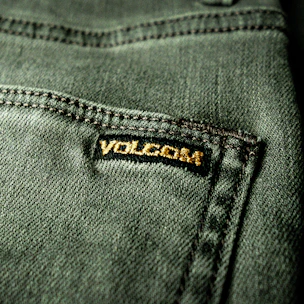 Premium woven label in black and gold tones sewn onto a stylish garment sleeve