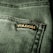 Close-up view of a textured green fabric featuring a visible seam and a small black label with gold embroidery.