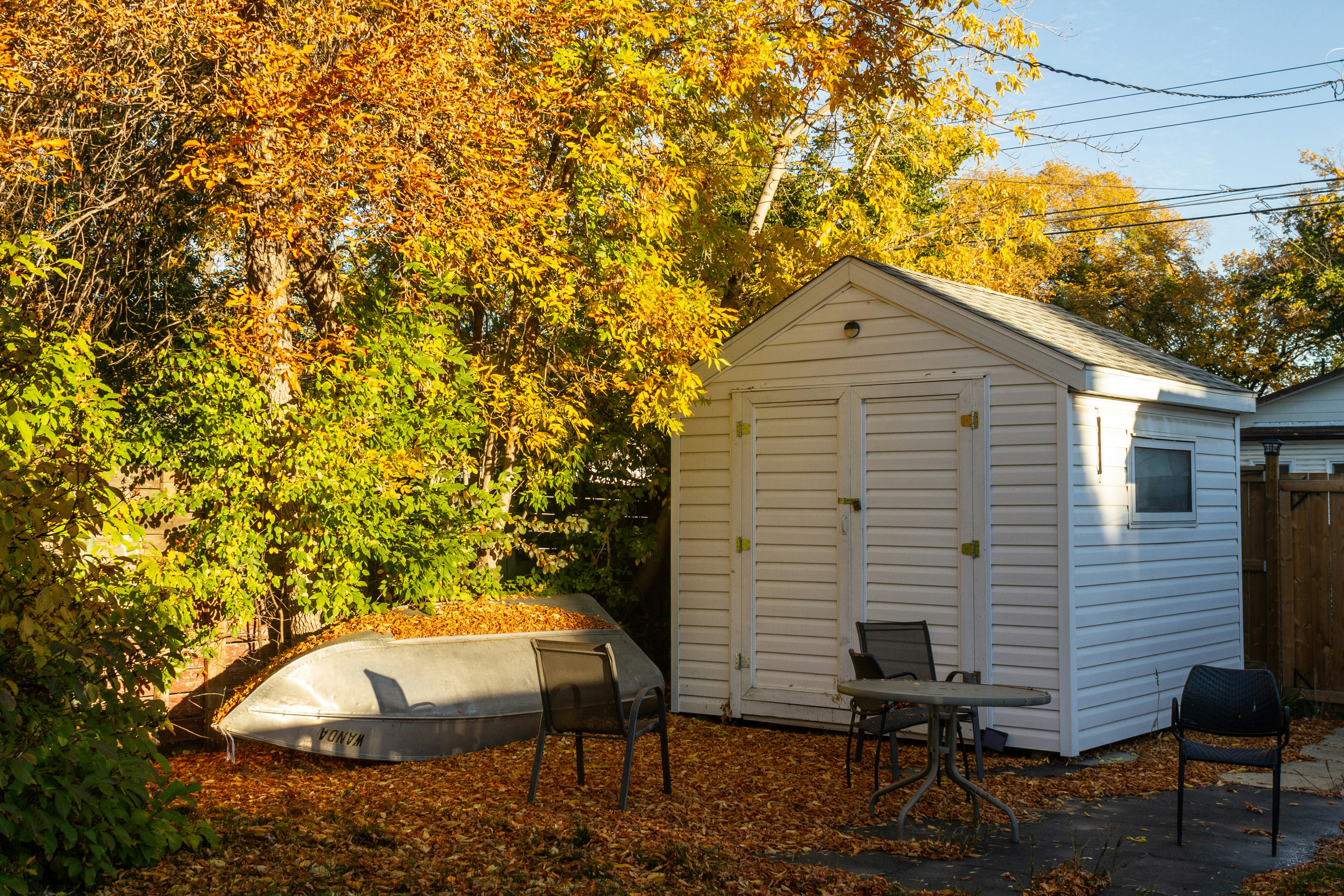 a small white shed with a boat in the yard