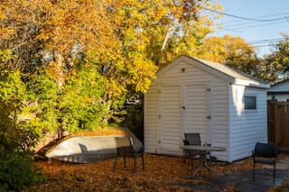 a small white shed with a boat in the yard