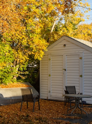 a small white shed with a boat in the yard