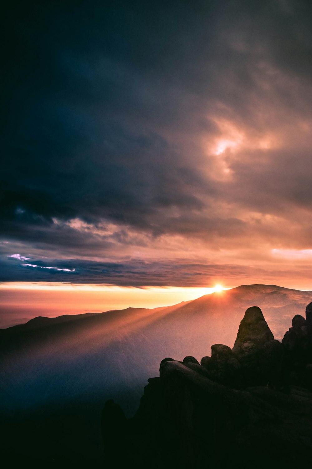 a person standing on top of a mountain under a cloudy sky