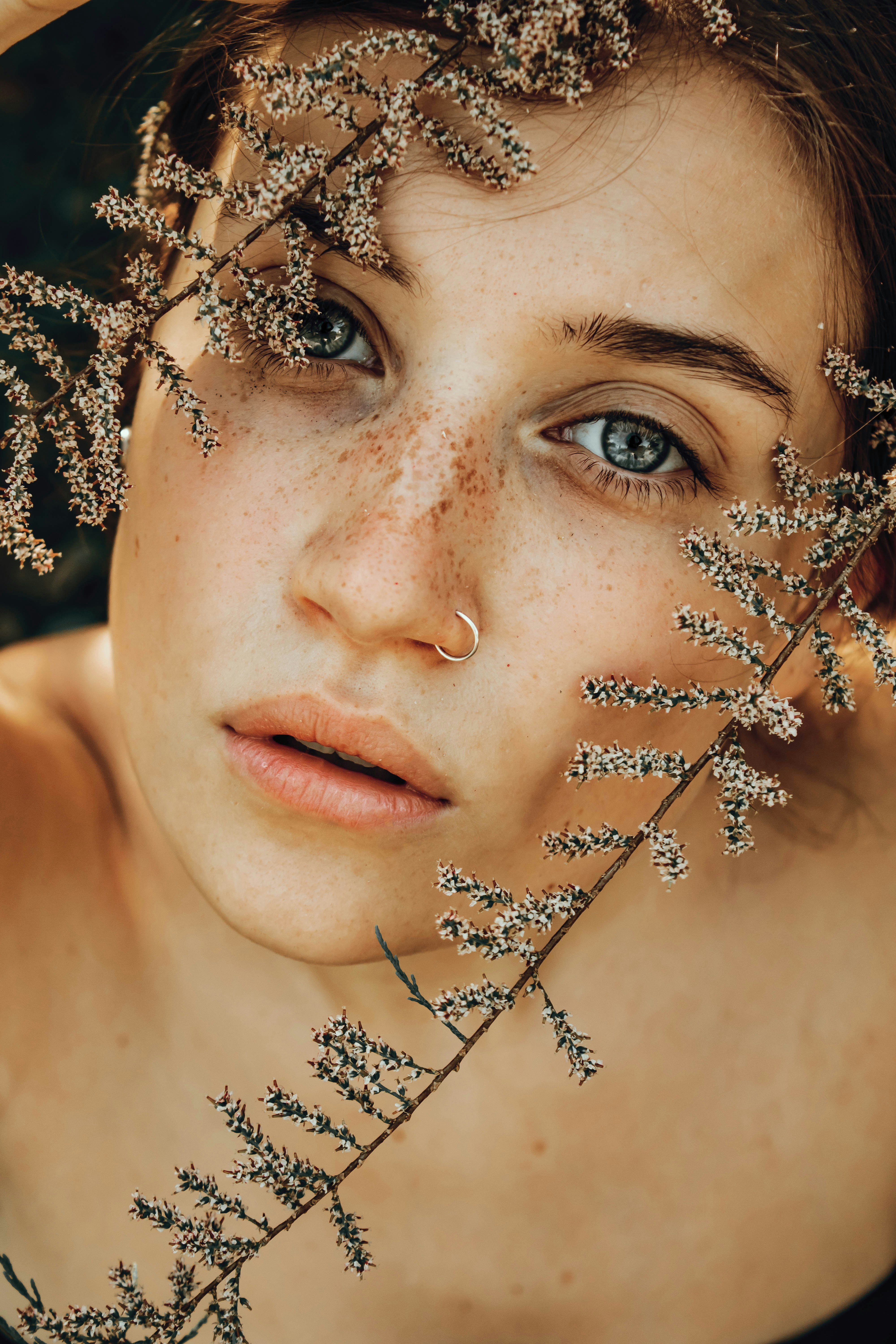 Une jeune femme aux taches de rousseur encadrées de branches délicates