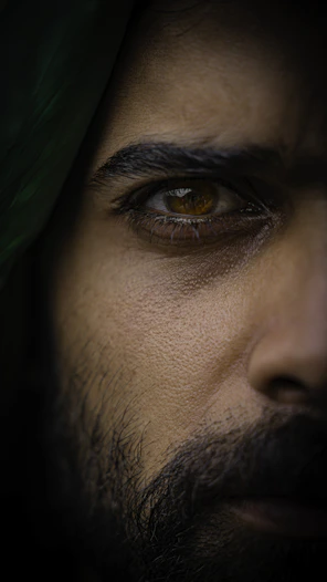 a close up of a man's face with a green shawl on his