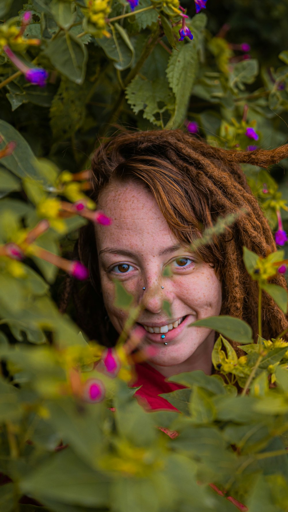 a woman with dreadlocks standing in a field of flowers