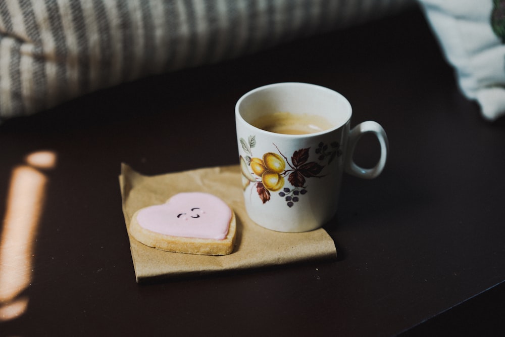 a cup of coffee and a heart shaped cookie on a napkin