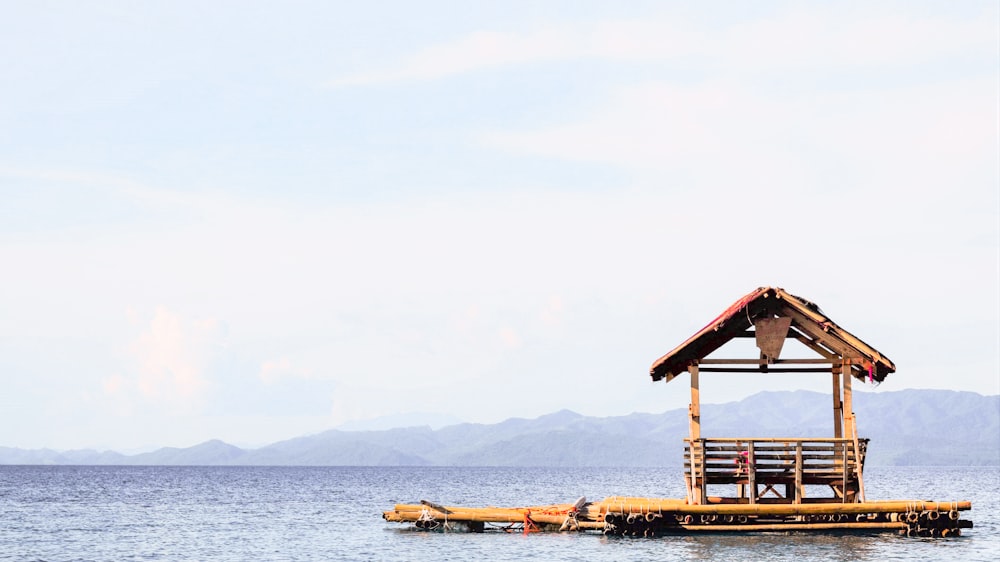 a dock with a hut on top of it in the middle of the ocean
