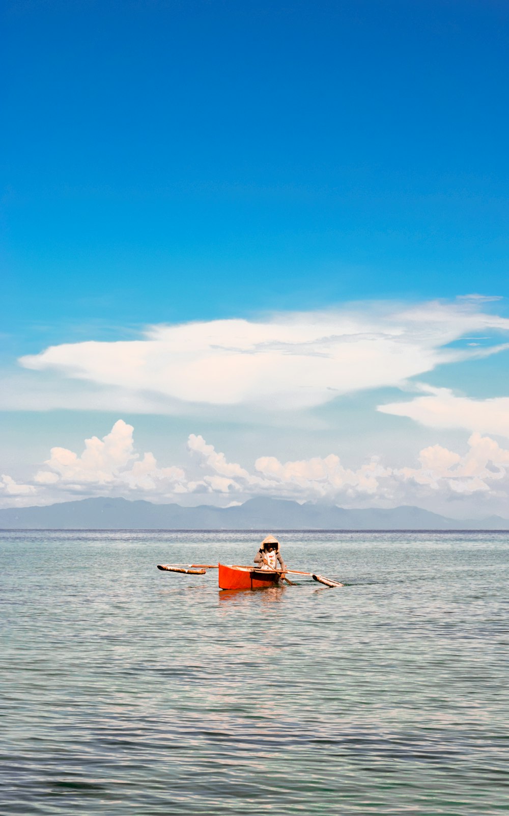 a man in a red boat on a large body of water