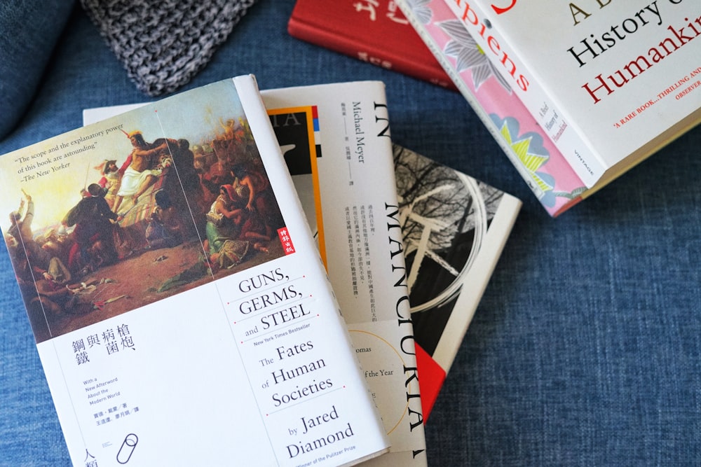 a pile of books sitting on top of a blue couch