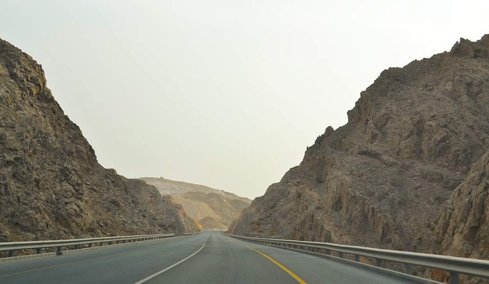 a car driving down a mountain road next to a mountain