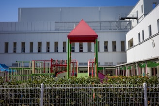a red and green play structure in front of a building