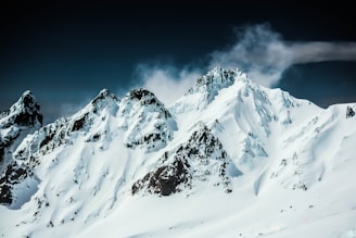 a mountain covered in snow under a cloudy sky