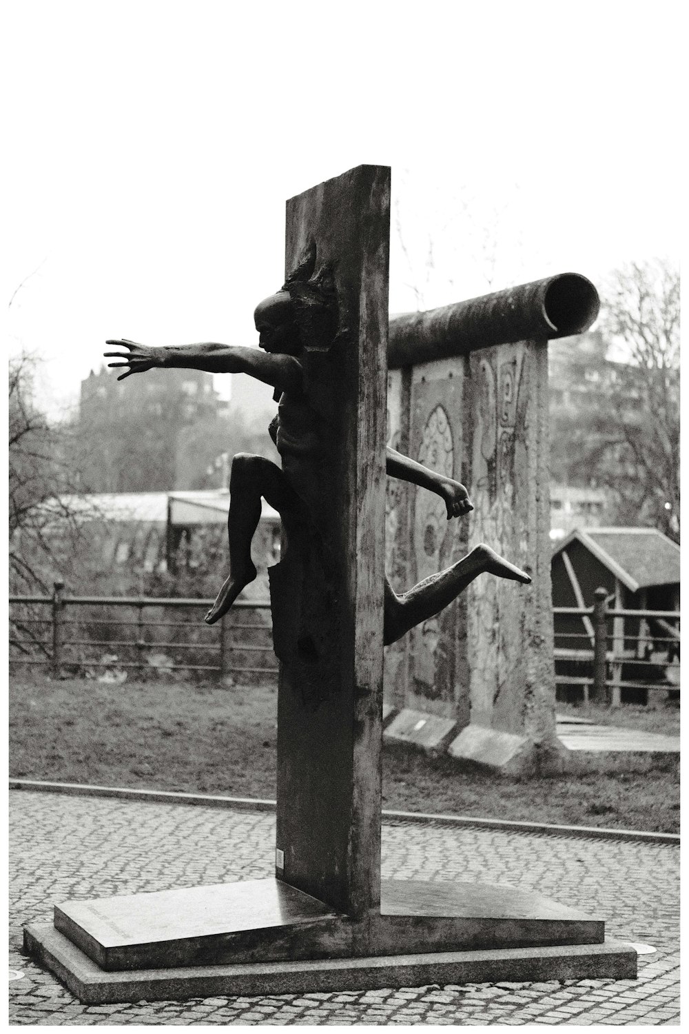 Una foto en blanco y negro de una estatua de un hombre en un poste de madera