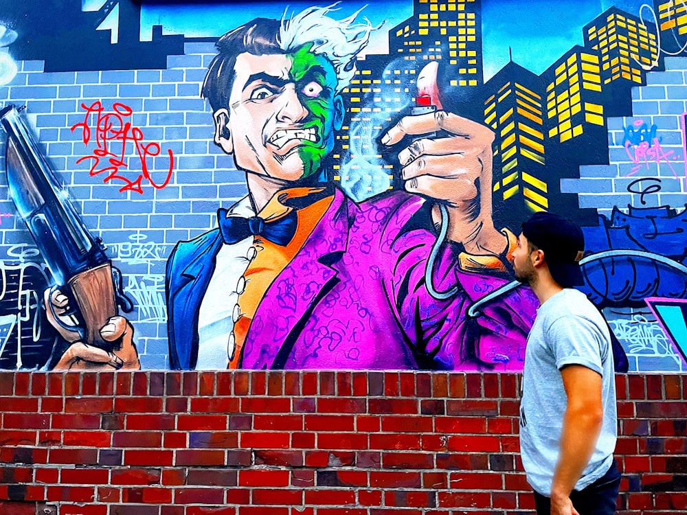 a man standing in front of a wall with a painting of a man holding a