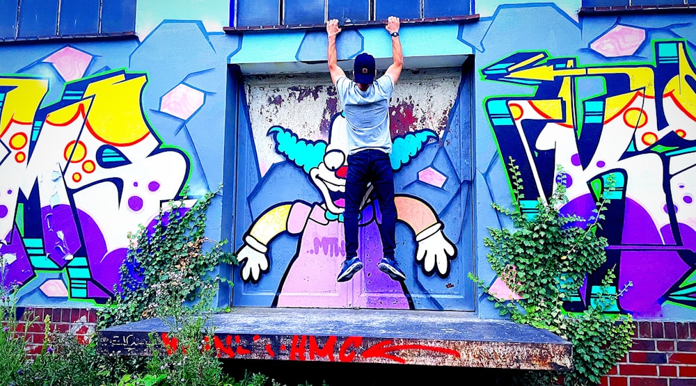 a man standing on a ledge in front of a colorful wall