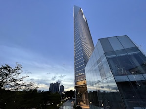 A sleek, modern high-rise building set against a vibrant city skyline at dusk.