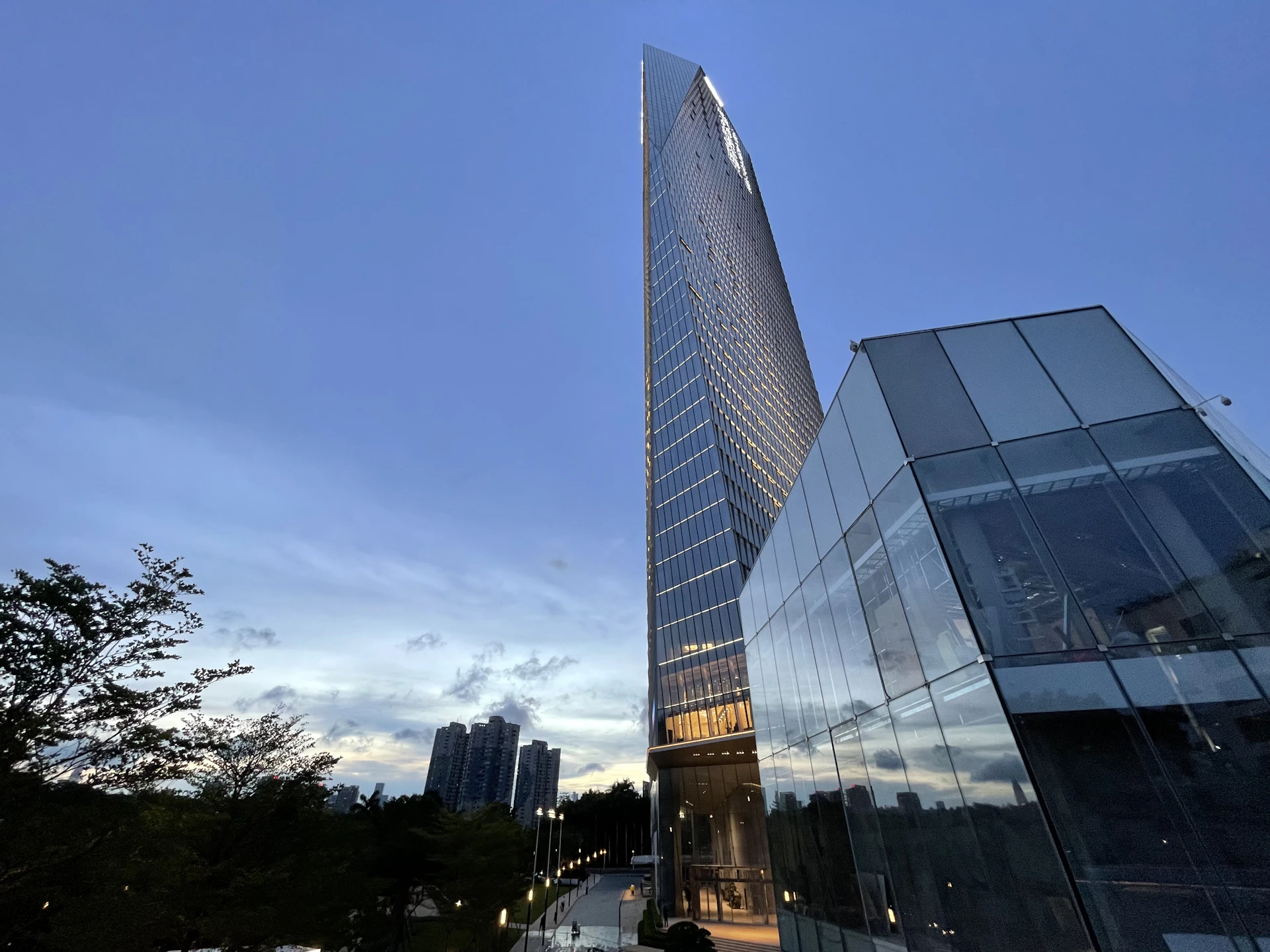 An elegant commercial building with sharp lines and reflective windows, captured at dusk revealing the city skyline.