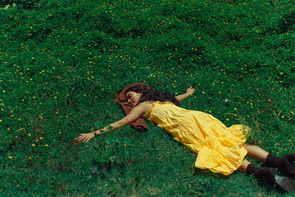 a woman in a yellow dress laying on the ground