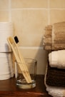 two wooden toothbrushes in a glass on a table