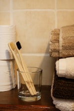 two wooden toothbrushes in a glass on a table