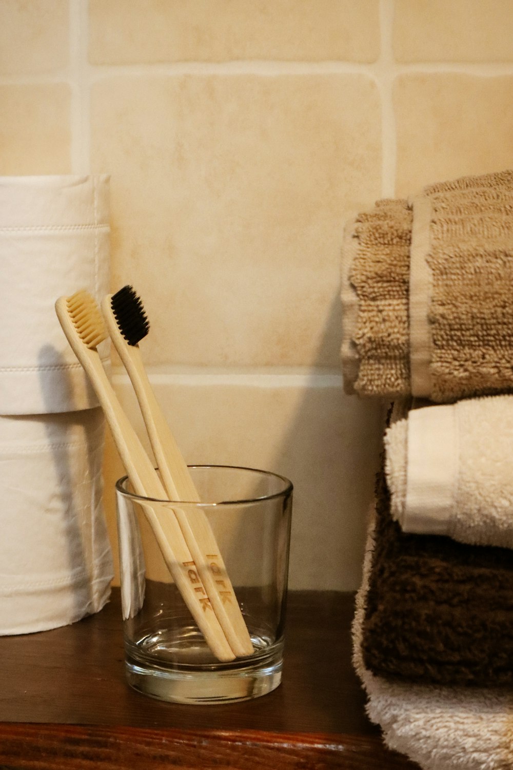 two wooden toothbrushes in a glass on a table