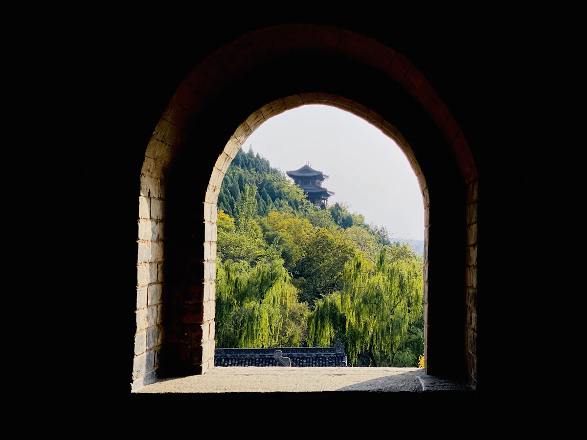 A pagoda on a wooded hill, framed by a stone arch in Yuncheng