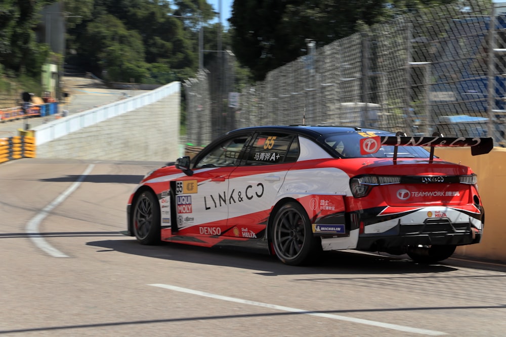 a red and white car driving down a race track