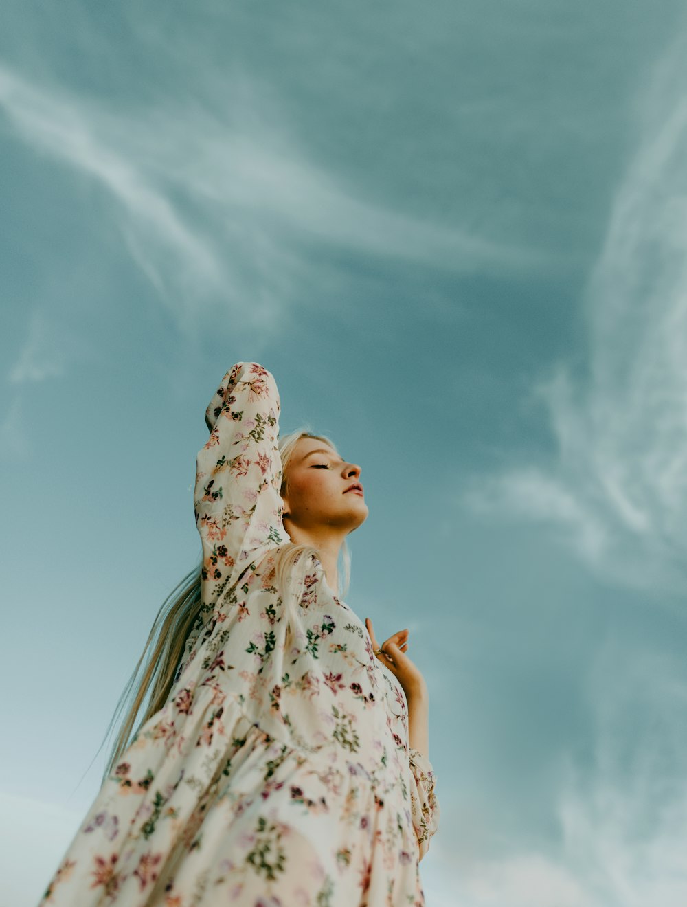 a woman in a floral dress looking up into the sky