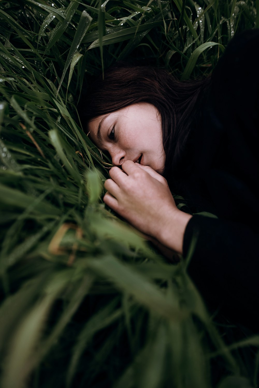 a woman laying in a field of tall grass