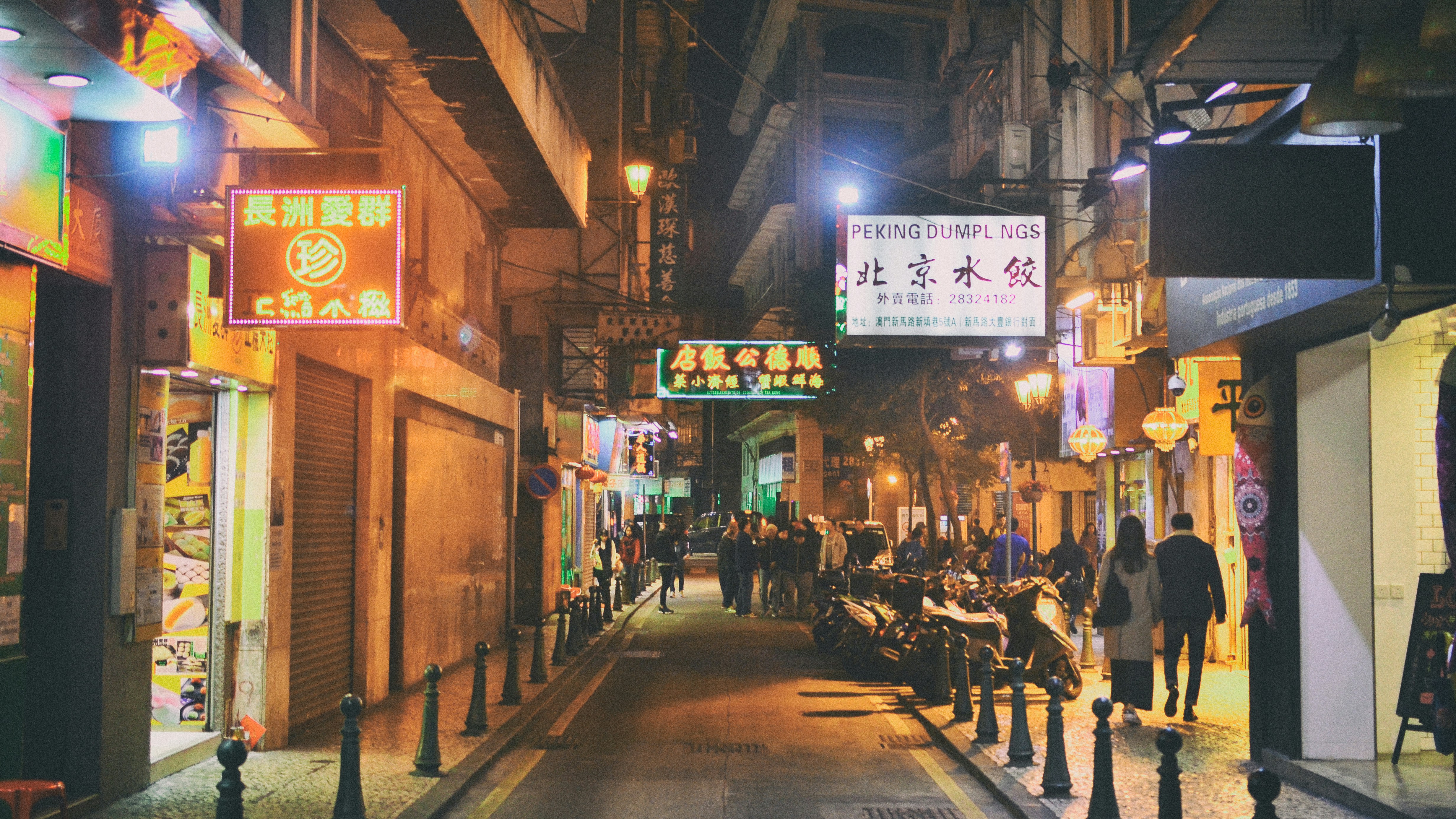 a city street at night with people walking on the sidewalk