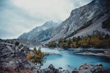 a body of water surrounded by mountains under a cloudy sky