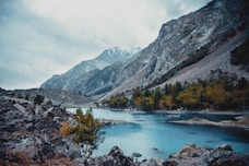 a body of water surrounded by mountains under a cloudy sky