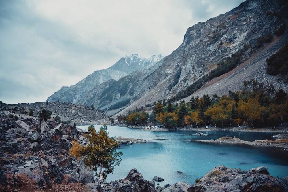 a body of water surrounded by mountains under a cloudy sky