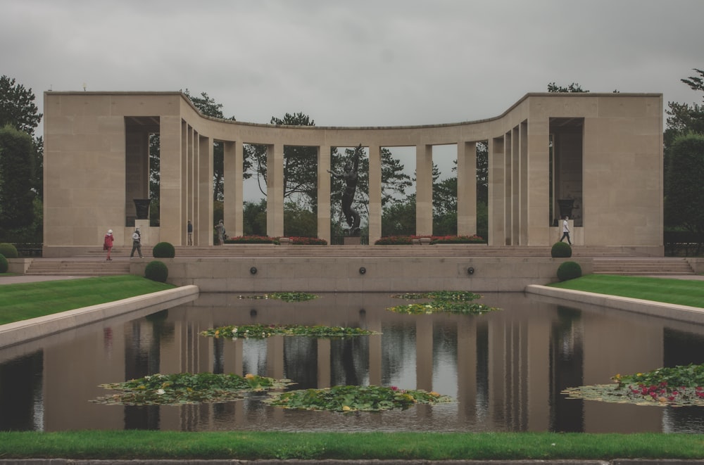 a pond in front of a building with columns